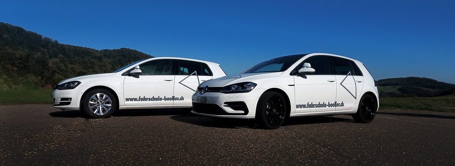 Die beiden weissen Fahrschulautos von Urs Böller vor blauem Himmel